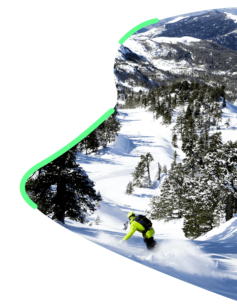 skieur en train de dévaler une piste de ski enneigé au milieu des sapins 