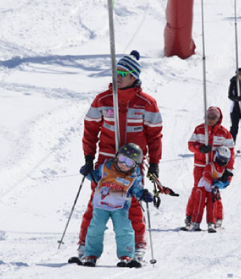 montieur de ski avec enfant utilisant les tirres fesses de la station