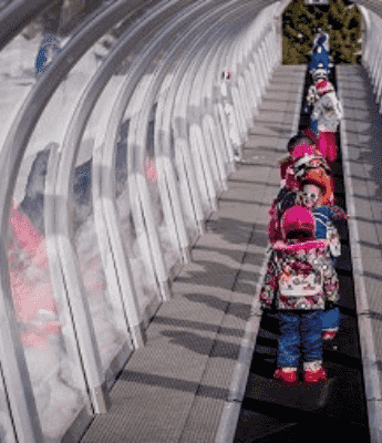 image esf groupe de jeunes élève en train d'emprunter le tapis sous un tunnel en verre sur staiton de ski luz ardiden